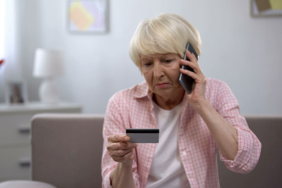 sad older lady with card on phone