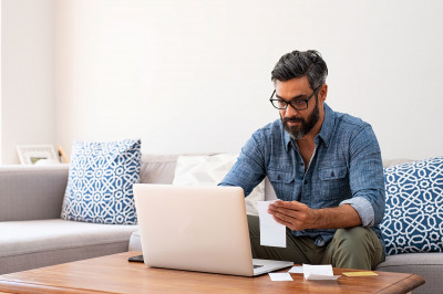 man on computer with receipts