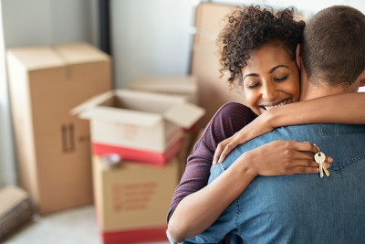 couple hugging with house keys surrounded by moving boxes