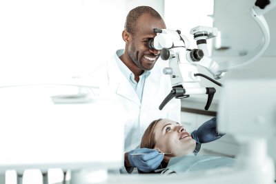 doctor looking into microscope at patient